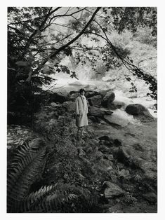 black and white photograph of a woman standing in front of a waterfall