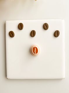 a white switch plate with coffee beans on it and an orange button in the middle