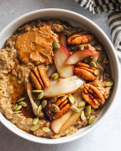 a bowl filled with oatmeal topped with apples and pecans