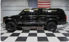 a black truck parked in a garage next to an american flag