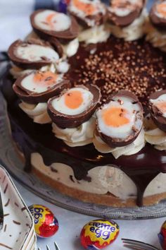 a chocolate cake with eggs on top and candies around the edges, sitting on a table