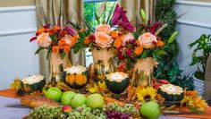 an arrangement of fruit and flowers on a table