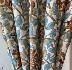 the curtains are hanging in front of a window with blue and brown flowers on them