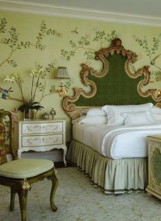 a bedroom with a green headboard and floral wallpaper on the walls, along with an ornate bed