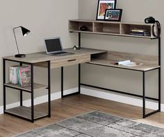 a computer desk with a laptop on top of it in front of a gray wall