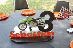 a small motorbike is on top of a table with orange plates and forks