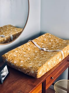 a bed sitting on top of a wooden dresser next to a mirror and table with a framed photo