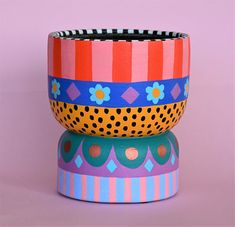 three colorful bowls are stacked on top of each other, one is decorated with flowers and dots