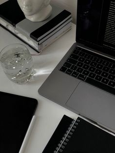 an open laptop computer sitting on top of a desk next to a glass of water