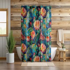 a colorful shower curtain in a bathroom with wood walls and flooring, along with a white bathtub