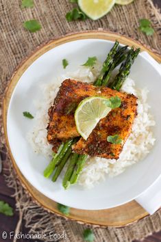 a white plate topped with rice and asparagus next to a lime wedge on top of it