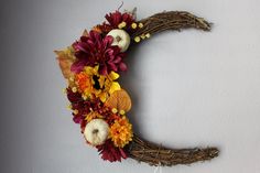 a wreath made to look like the moon is decorated with fall flowers and pumpkins