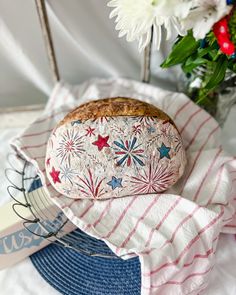 a loaf of bread sitting on top of a blue and white towel next to flowers