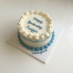 a white and blue birthday cake on top of a card that says happy birthday i love you