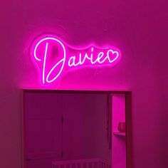 a pink neon sign that says daiec on the side of a wall next to a crib