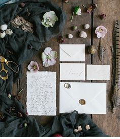 the wedding stationery is laid out on top of an old wooden table with flowers