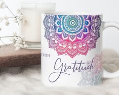 a coffee mug with the words grateful on it next to a candle and some flowers