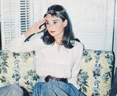 a woman sitting on top of a couch next to a window