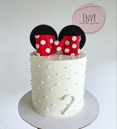 a white cake with red polka dots and mickey mouse ears on top, sitting on a table