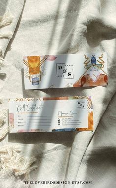 two tickets sitting on top of a bed next to each other with the words, gift certificate