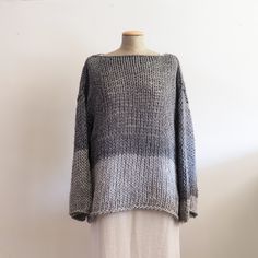 a woman's sweater on a mannequin stand in front of a white wall