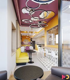 the interior of a modern restaurant with yellow and purple chairs, black round tables, and circular chandeliers