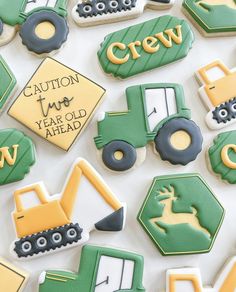 decorated cookies with tractors, trucks and construction signs are displayed on a white tablecloth