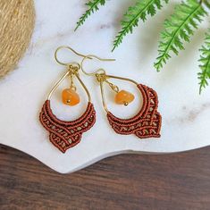 Carnelian and gold earrings with a rich mahogany orange macrame detail. Handmade to order with love 💕 ❃ 1 pair of macrame earrings featuring an Carnelian chip bead. ❃ These earrings come with vacuum plated gold stainless steel ear wires ❃ Knotted with durable, nylon cord (mahogany) ❃ Choose your ear hook style. (All hooks come with clear backings except for the closable hooks) :  1.  Gold stainless steel french hooks: The finish is vacuum plated for a durable gold finish. 2. Leverback: These hooks latch in the back for a secure fit. Also vacuum plated gold finish. 3. Plastic hooks: These are made of a flexible clear plastic. Perfect for sever metal allergies. ❧ All accessories by Hang Loose Creations are uniquely handcrafted, using deep-rooted macrame techniques ❧ With Boho designs and he Handmade Orange Brass Earrings, Handmade Bohemian Amber Earrings, Handmade Amber Bohemian Earrings, Handmade Adjustable Carnelian Earrings, Bohemian Orange Copper Earrings, Orange Copper Bohemian Earrings, Bohemian Orange Brass Jewelry, Handmade Carnelian Orange Earrings, Orange Macrame Jewelry As Gift