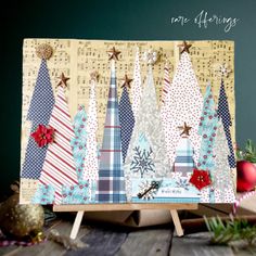 a christmas card with trees on it and decorations around the edges, sitting on a wooden table