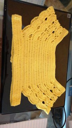 a yellow crocheted piece of cloth sitting on top of a computer monitor screen