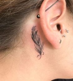 a woman's behind the ear tattoo with a feather