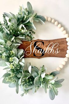 a wooden sign with the word shaks on it surrounded by greenery and beads