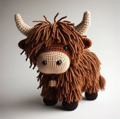 a crocheted cow with long hair standing in front of a white background