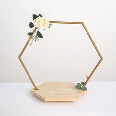 a wooden hexagonal stand with a white rose on it