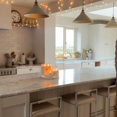 a kitchen with an island and lights hanging from the ceiling