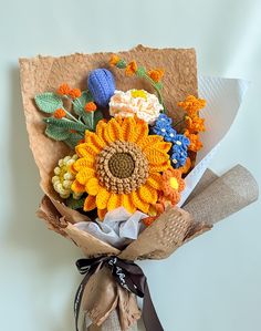 a bouquet of sunflowers and other flowers is wrapped in burlap paper