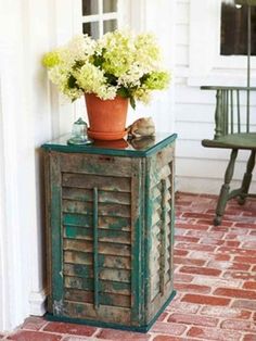 a potted plant sitting on top of a wooden cabinet next to a green chair