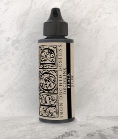 a bottle of black ink sitting on top of a white marble countertop next to a wall