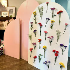 flowers are arranged on the wall in front of a pink arch with white walls and wood flooring