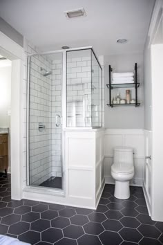 a bathroom with a toilet, shower and tiled flooring in black and white colors