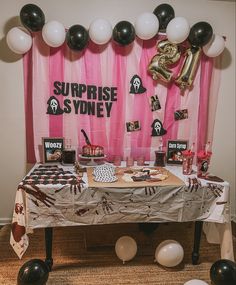 a table topped with lots of desserts and balloons in front of a pink backdrop