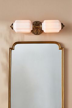 a bathroom vanity with a mirror and two lights on it's side, against a beige wall