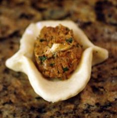 a small dumpling with meat and cheese on it sitting on a granite countertop