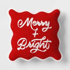 a red pillow with white lettering on it that says merry and bright in the middle