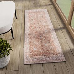 an area rug is on the floor next to a chair and potted plant in front of a window