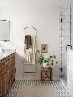 a bathroom with white tile and wooden cabinets, an old ladder as a towel rack