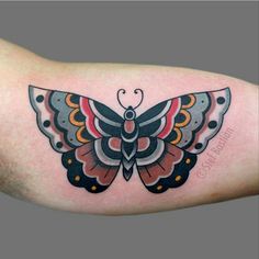 a colorful butterfly tattoo on the right arm and shoulder, with dots around it's wings