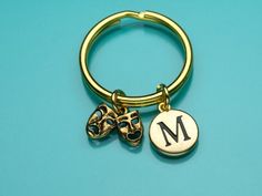 a gold keychain with two charms attached to it on a blue background that says m