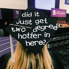 a woman wearing a graduation cap with the words did it just get two degrees in here?