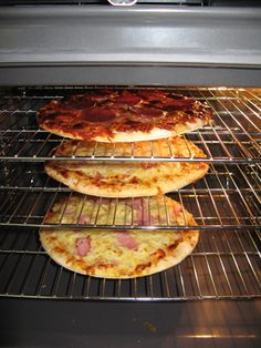 three pizzas sitting on top of each other in an oven